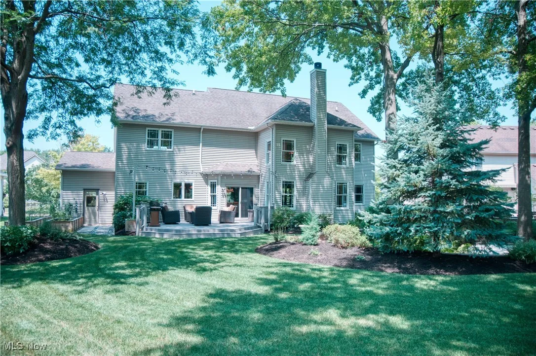 Back of property featuring a chimney, a yard, and a shingled roof