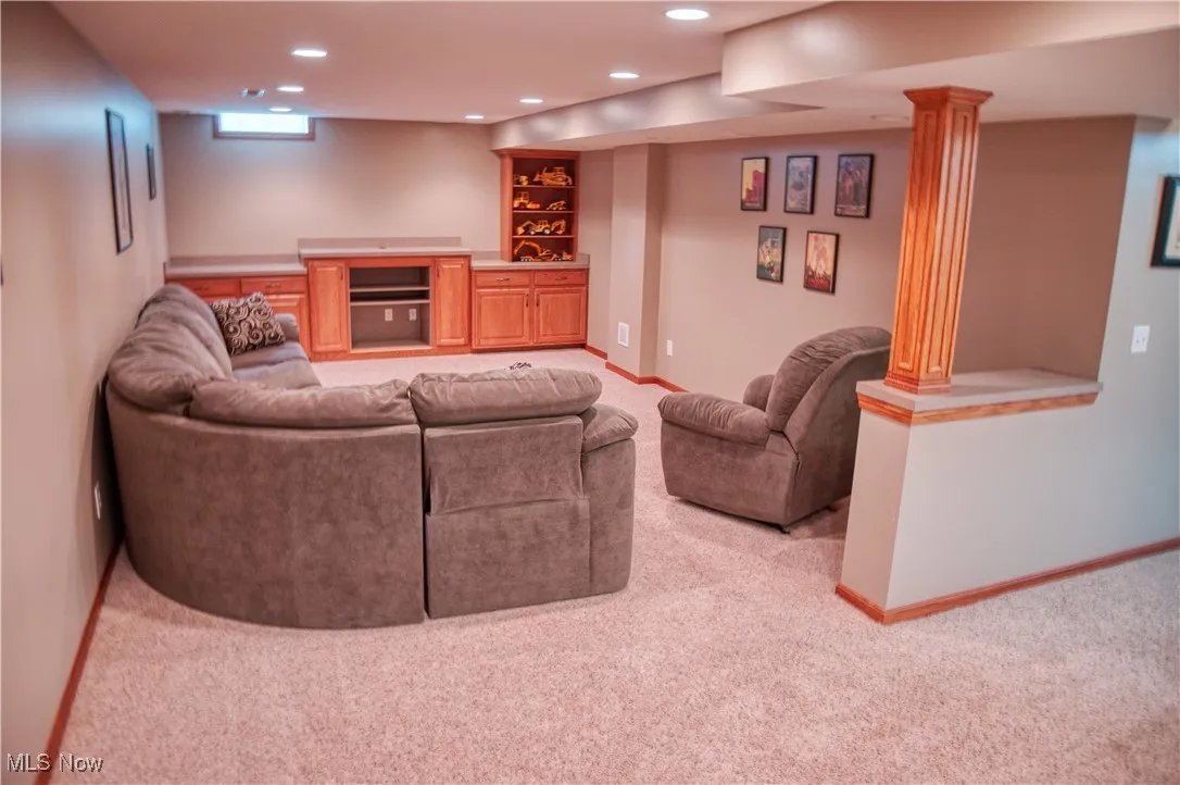 Carpeted living area with recessed lighting and ornate columns