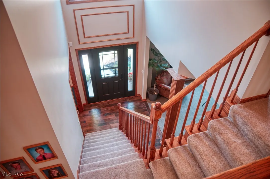 Entryway with a towering ceiling, stairway, and wood finished floors