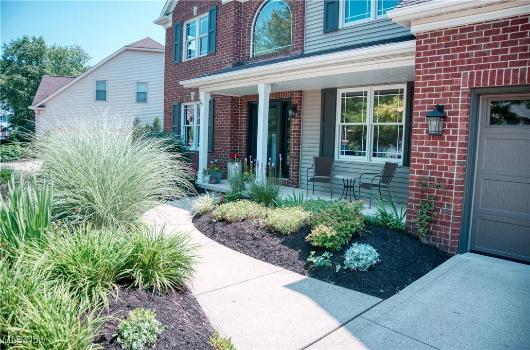 Doorway to property featuring brick siding and covered porch