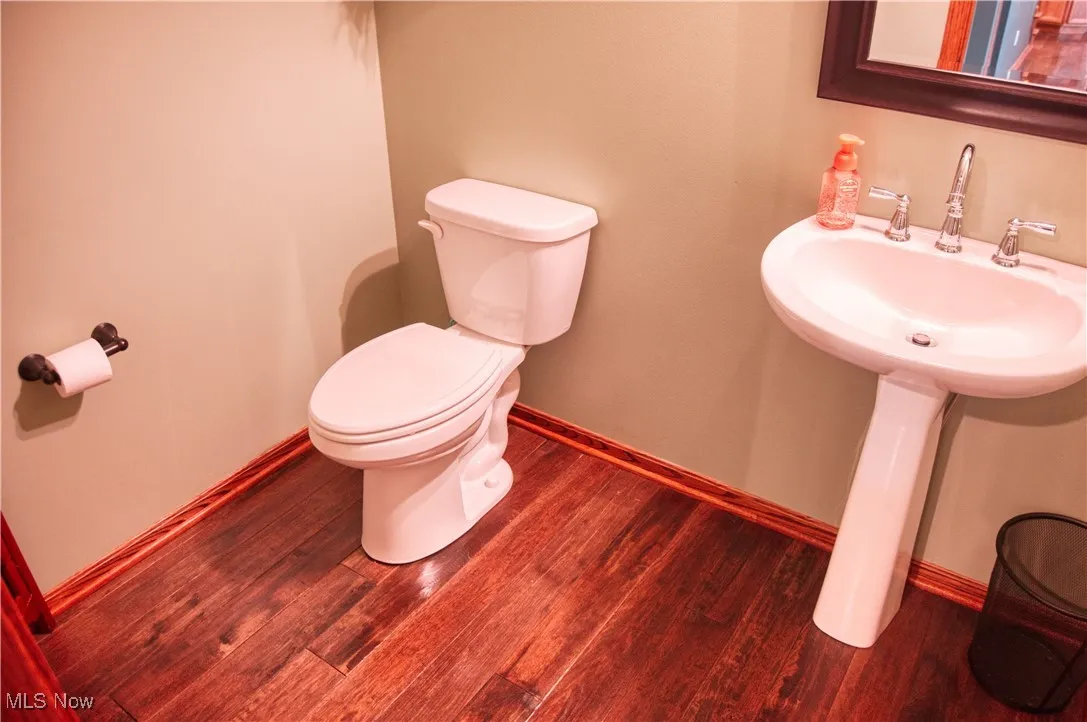 Half bath featuring toilet and wood finished floors
