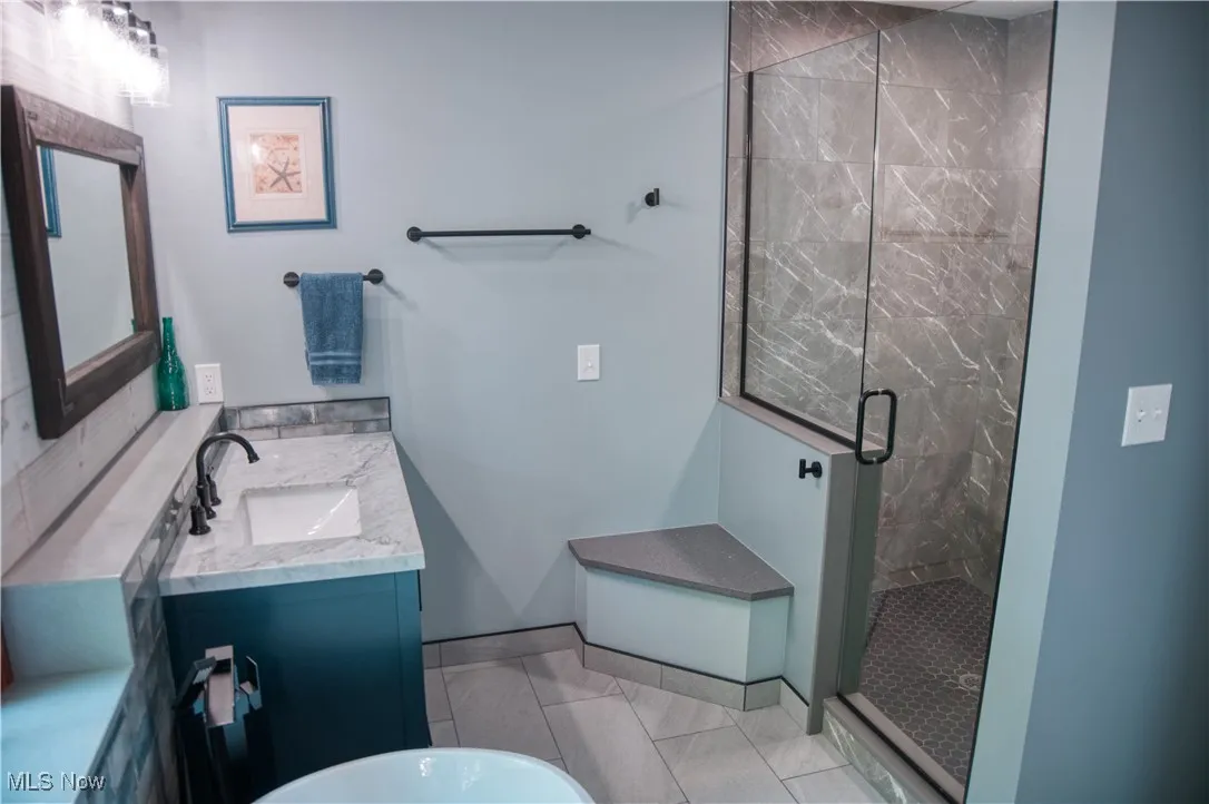 Full bathroom featuring a shower stall, vanity, and a freestanding bath