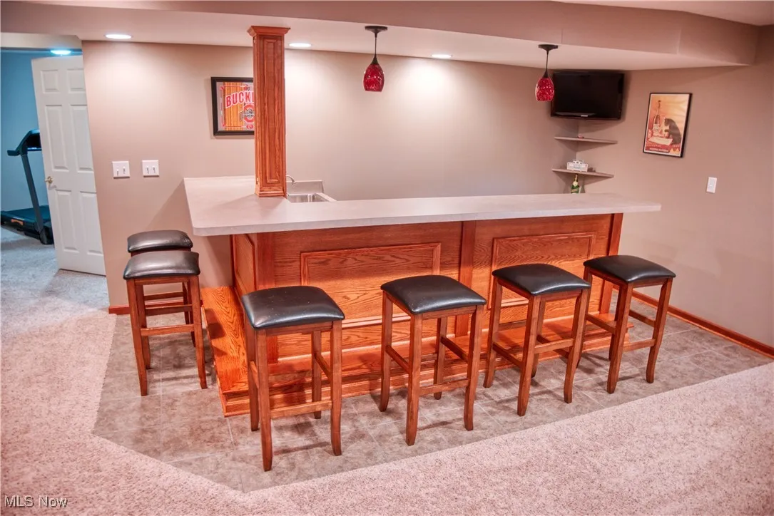 Indoor wet bar with light carpet, hanging light fixtures, and recessed lighting