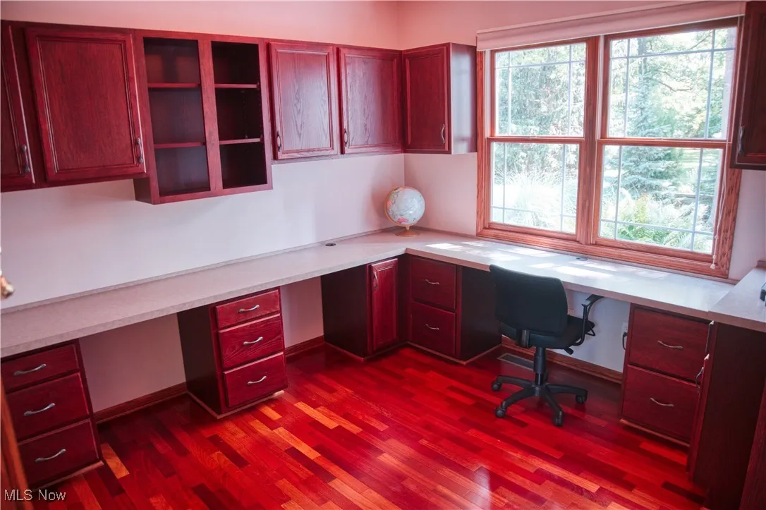 Unfurnished office featuring built in study area and dark wood-type flooring