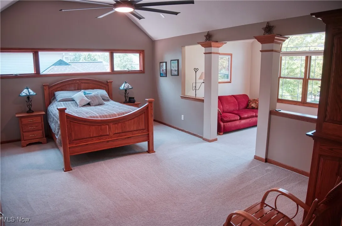 Bedroom with light carpet, vaulted ceiling, and ceiling fan