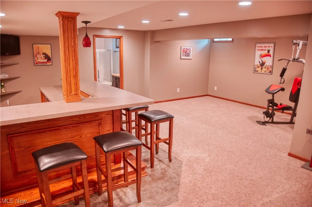 Indoor dry bar featuring recessed lighting, light carpet, decorative columns, and pendant lighting
