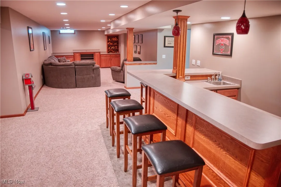 Indoor wet bar with recessed lighting, light carpet, and pendant lighting