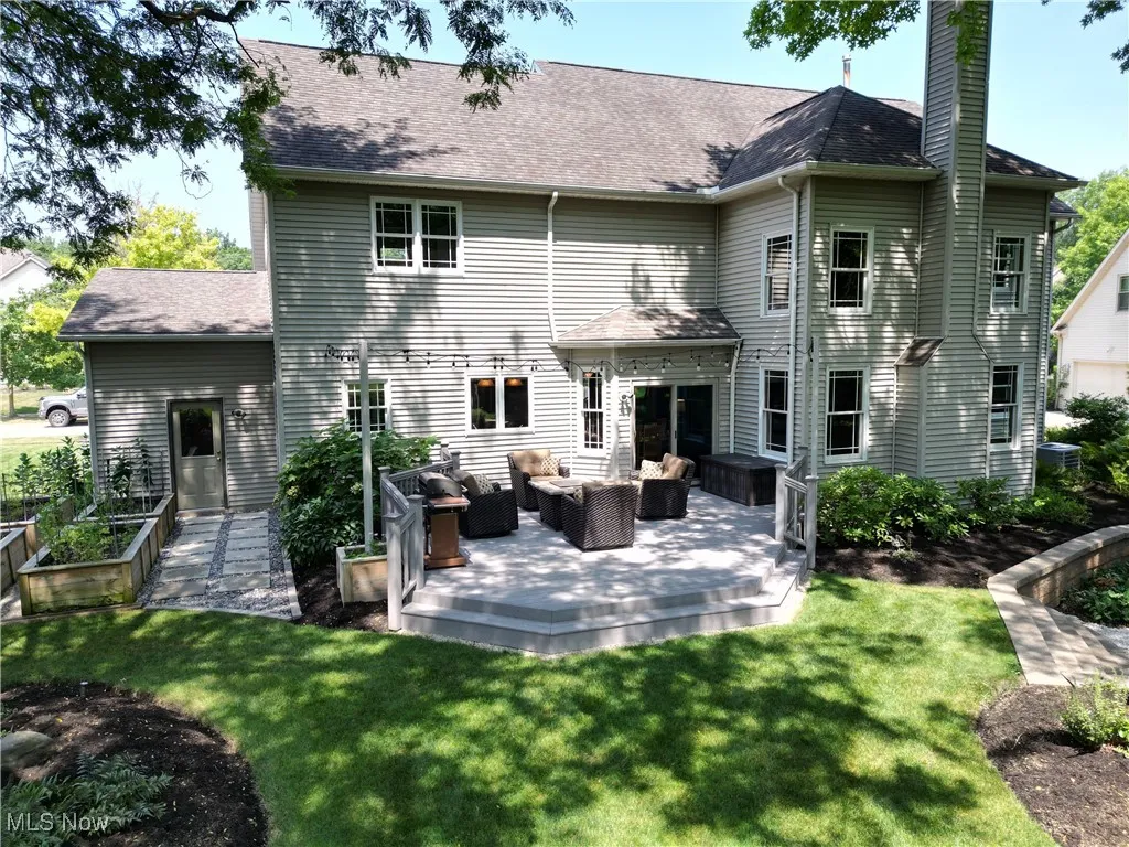 Rear view of house with a yard, an outdoor living space, a patio, and a shingled roof
