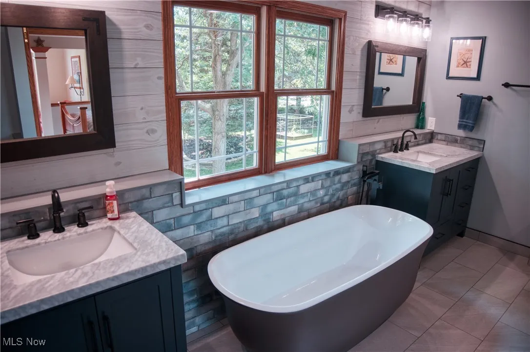 Bathroom with two vanities, a freestanding bath, and tile patterned flooring