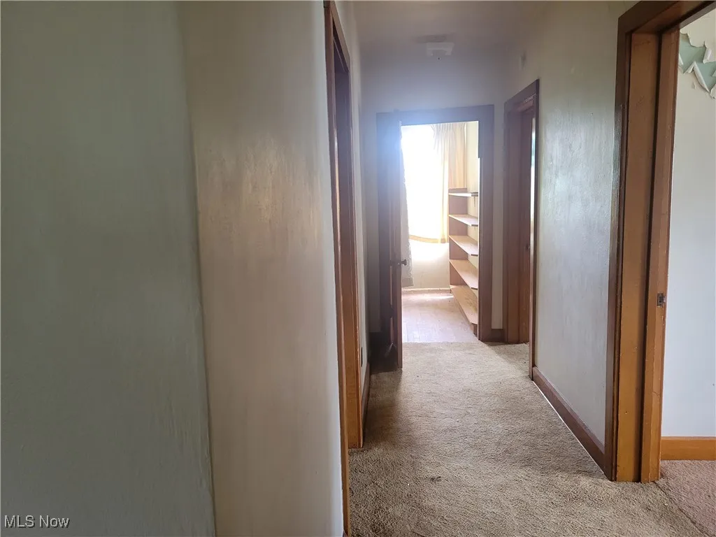Hallway featuring light carpet and baseboards