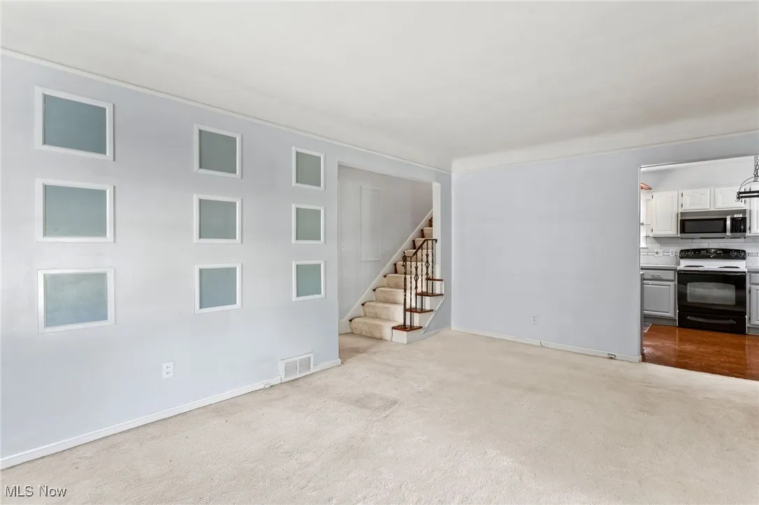 Unfurnished living room with stairway and carpet flooring