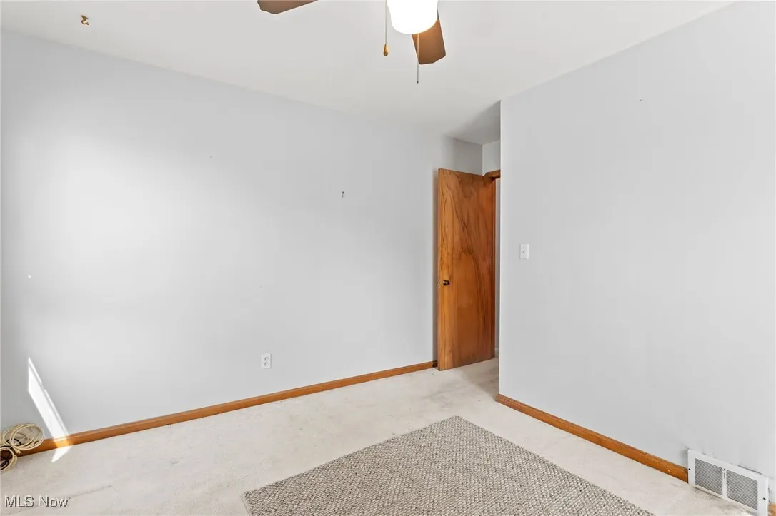 Unfurnished room with light colored carpet and ceiling fan