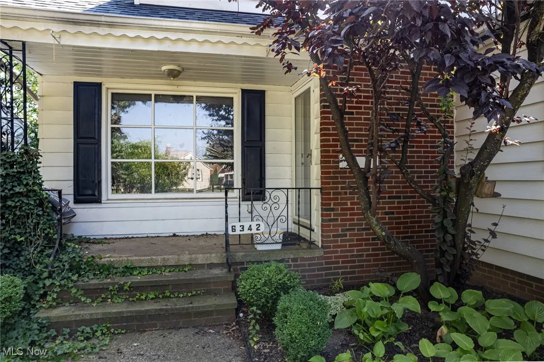 Property entrance featuring a shingled roof and covered porch