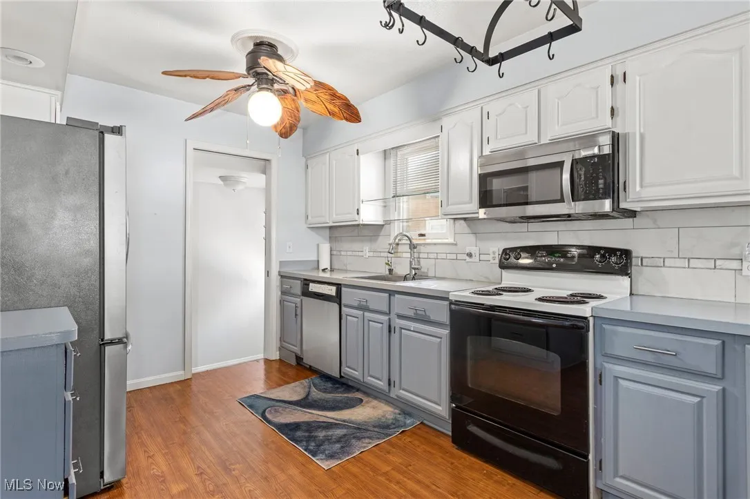 Kitchen with appliances with stainless steel finishes, gray cabinets, a ceiling fan, and backsplash
