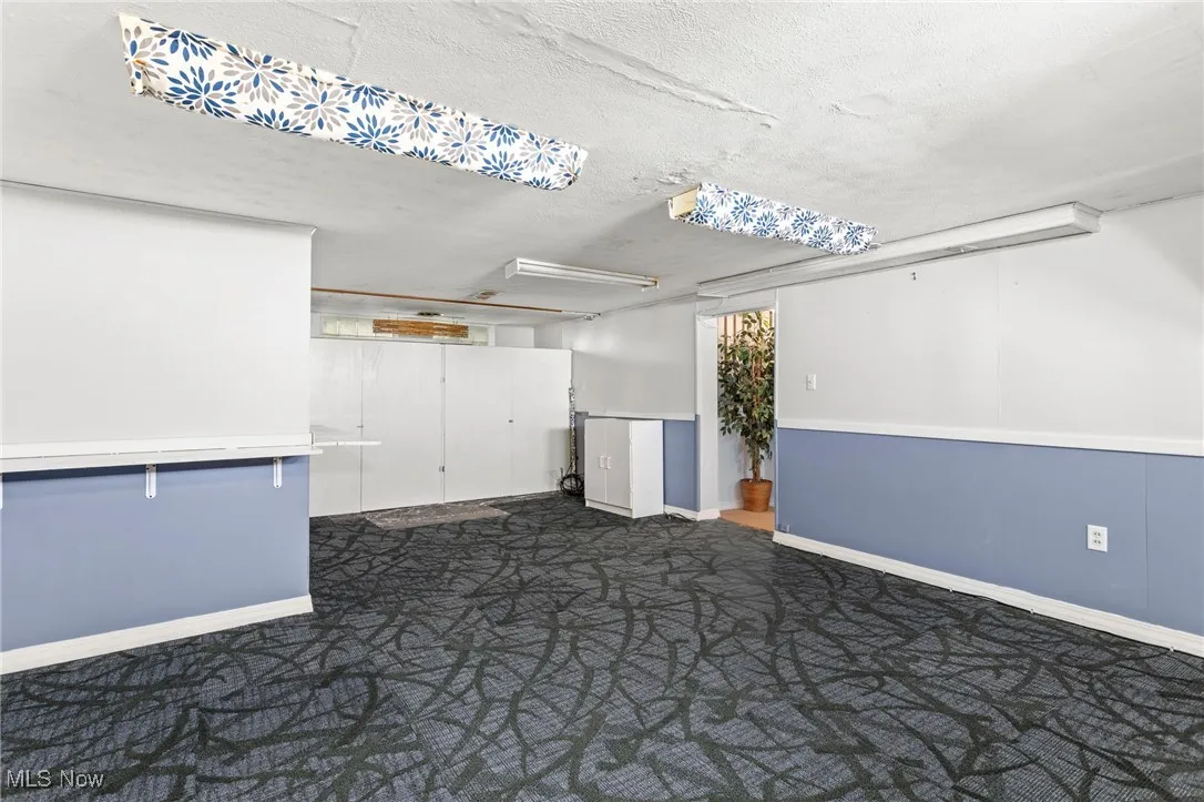 Finished below grade area with dark colored carpet and a textured ceiling