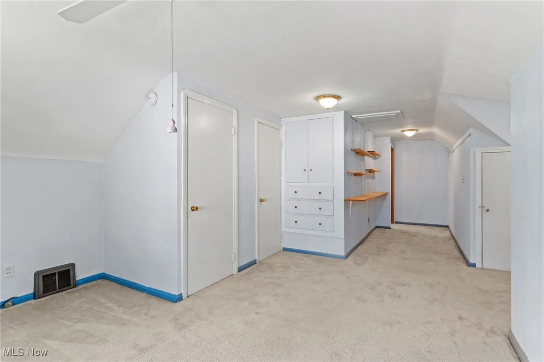 Bonus room featuring light colored carpet and vaulted ceiling