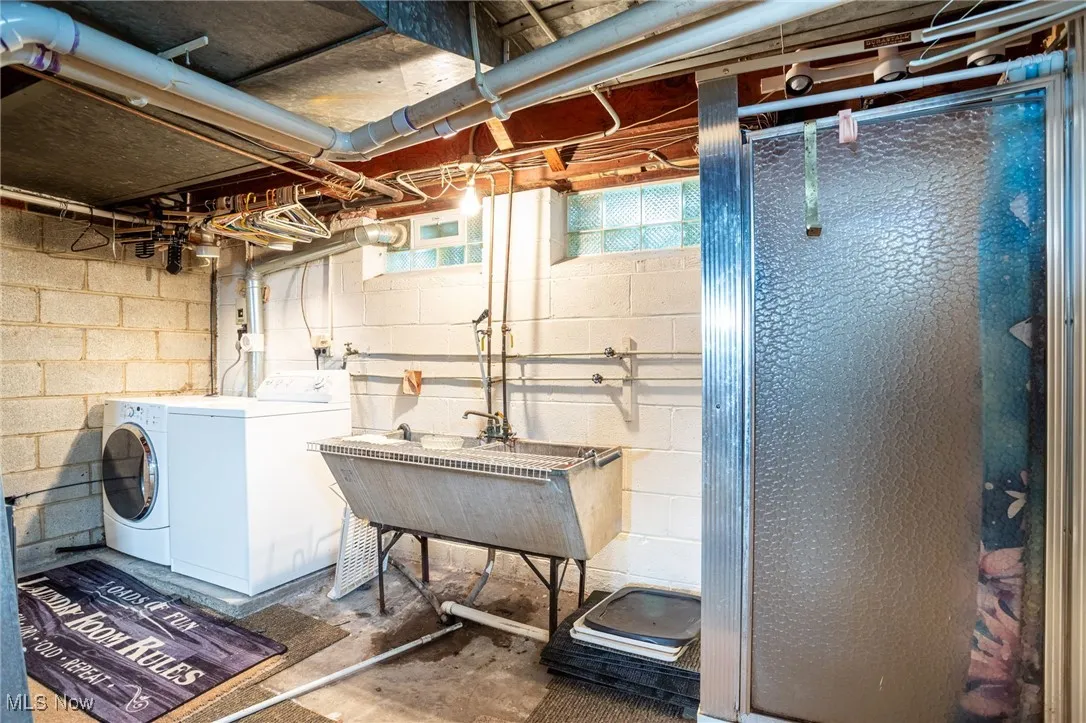 Basement featuring washer and clothes dryer and concrete block wall