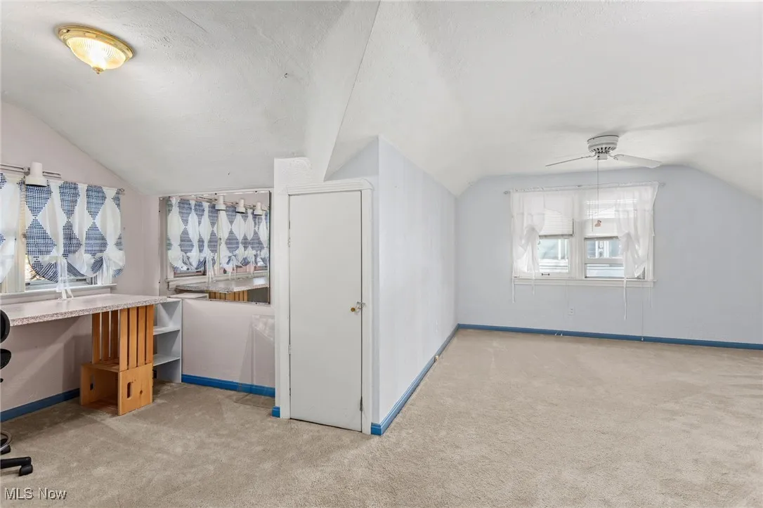 Additional living space with lofted ceiling, carpet floors, ceiling fan, and a textured ceiling