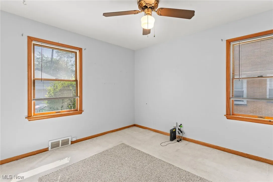 Carpeted empty room featuring baseboards and ceiling fan