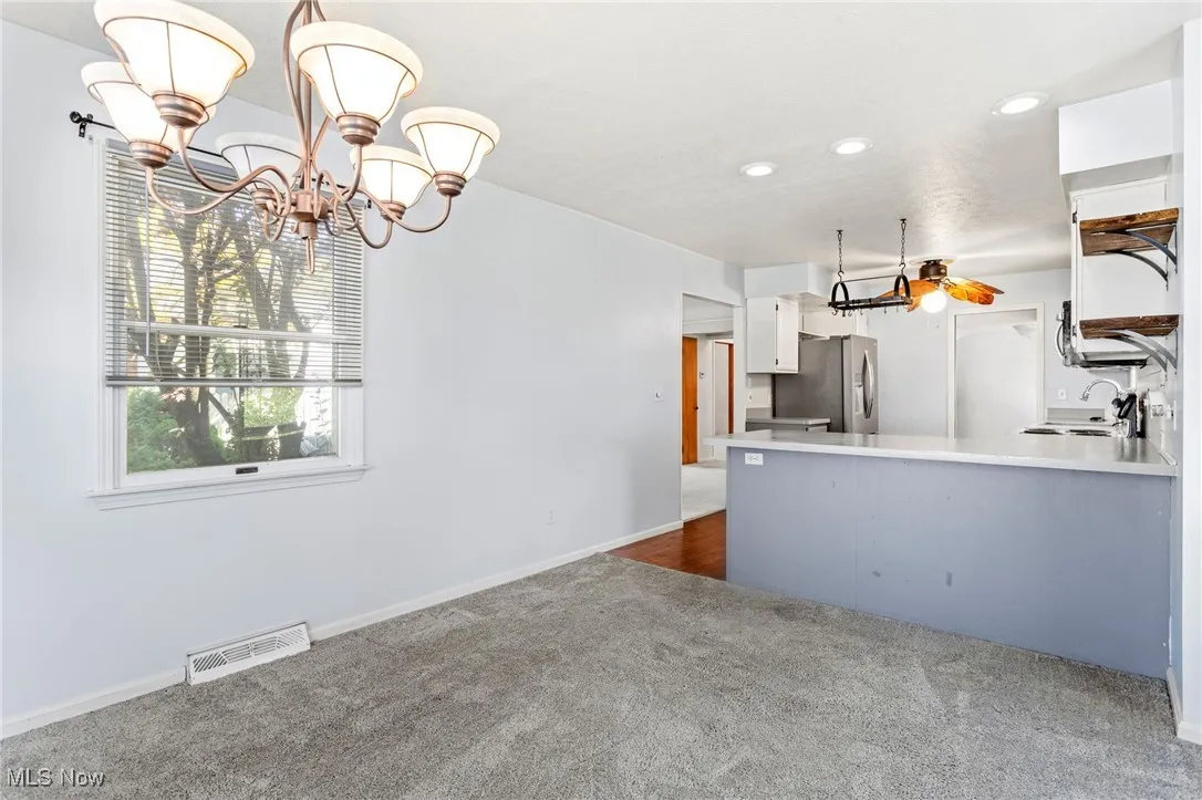 Kitchen featuring dark carpet, a chandelier, recessed lighting, white cabinets, and stainless steel refrigerator with ice dispenser