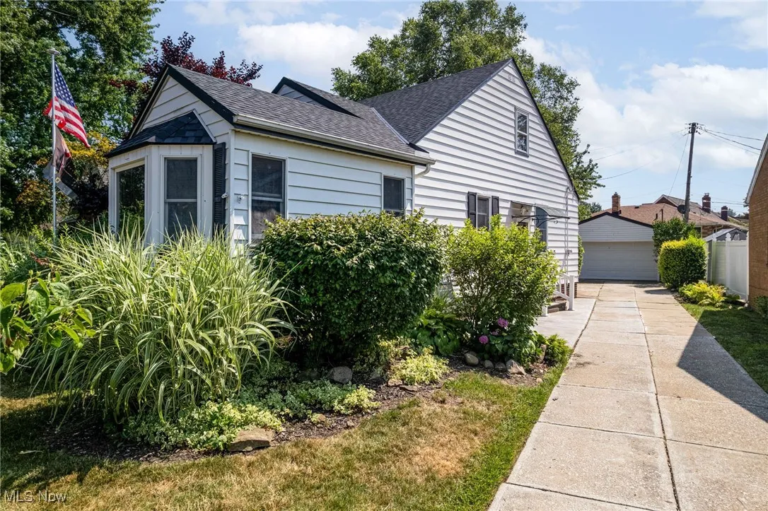 View of home's exterior with roof with shingles, a garage, and an outdoor structure