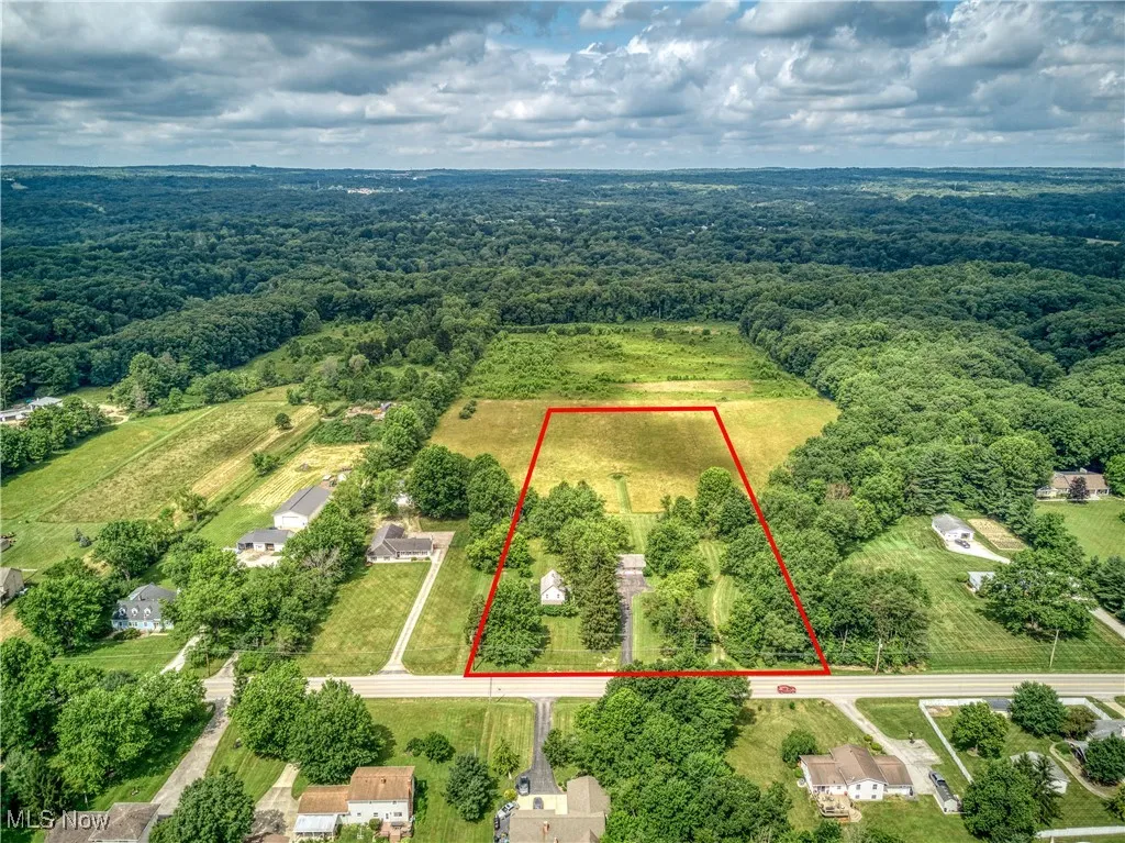 Aerial view of property's location with a heavily wooded area and approximate property parcel outlined