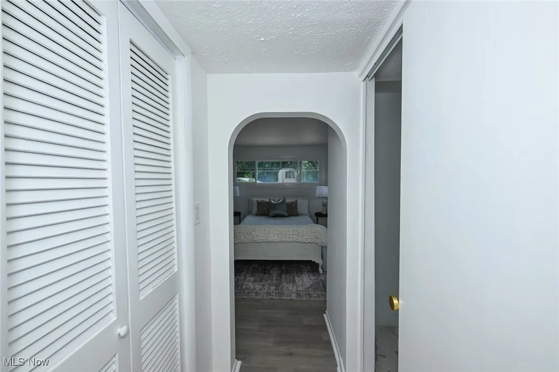 Corridor with wood finished floors, a textured ceiling, and arched walkways