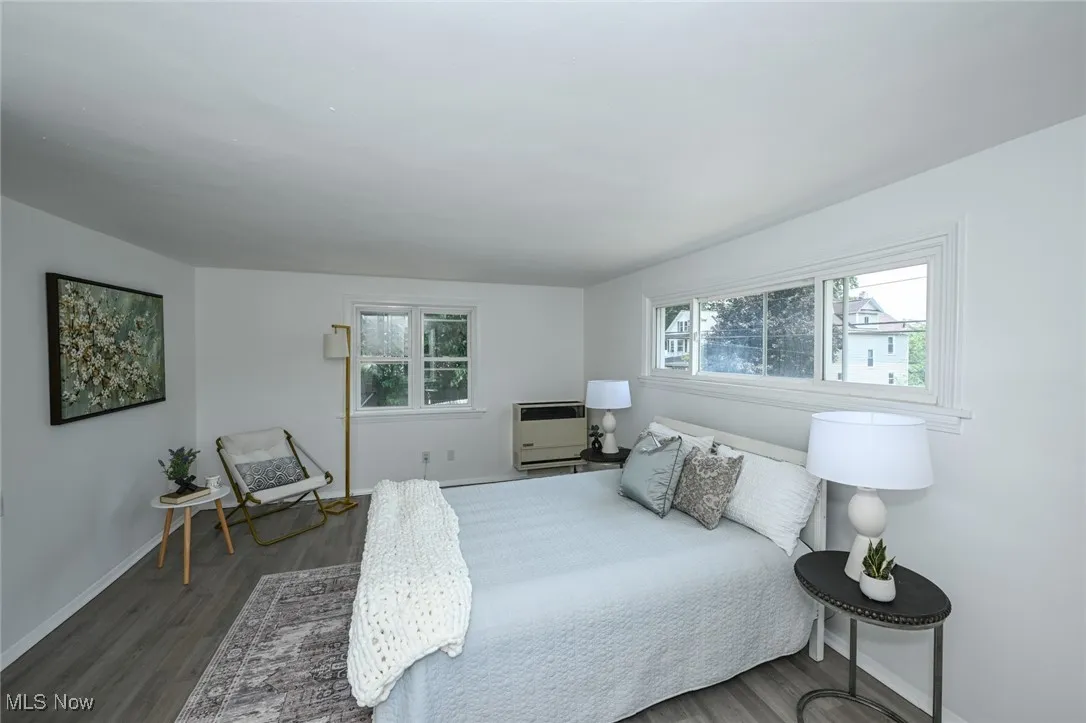 Bedroom featuring multiple windows, dark wood-style flooring, and heating unit