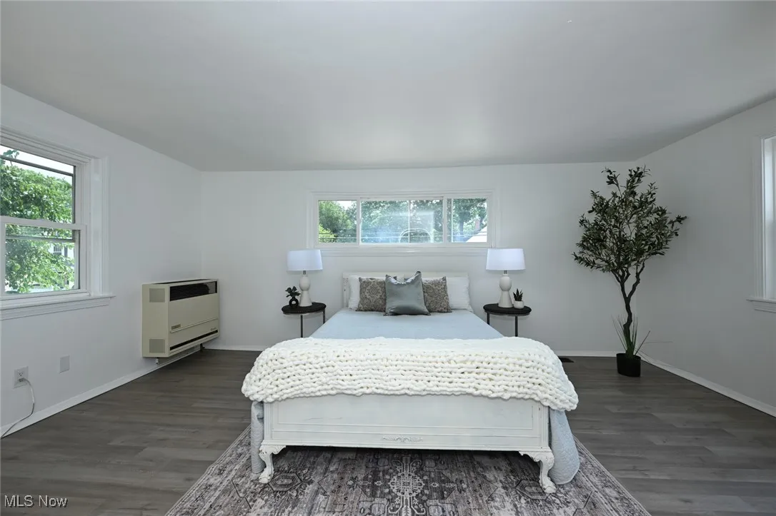 Bedroom featuring heating unit and dark wood-style floors