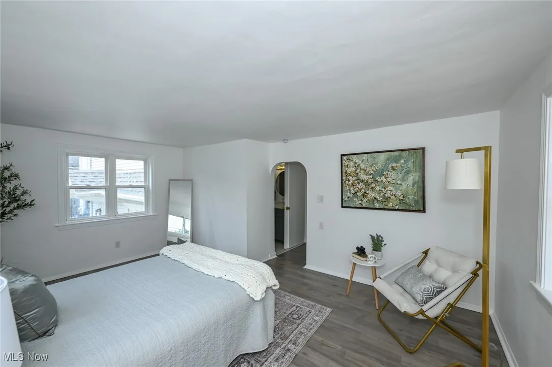 Bedroom with arched walkways and wood finished floors
