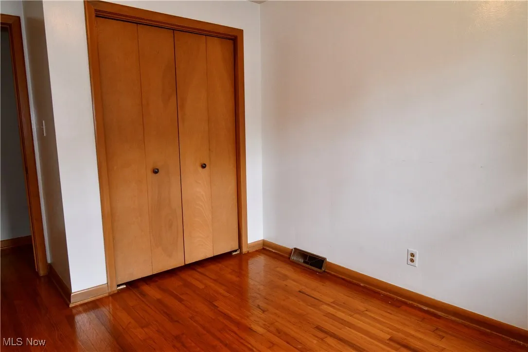 Unfurnished bedroom featuring dark wood-style flooring and a closet