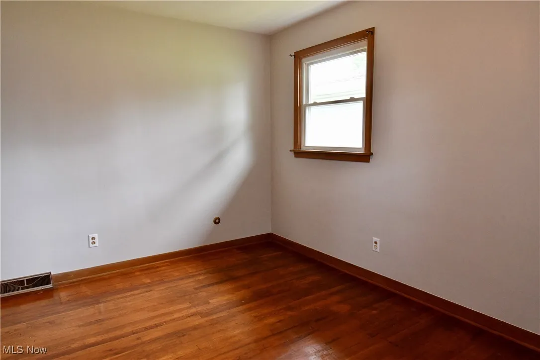 Unfurnished room with dark wood-style flooring and baseboards
