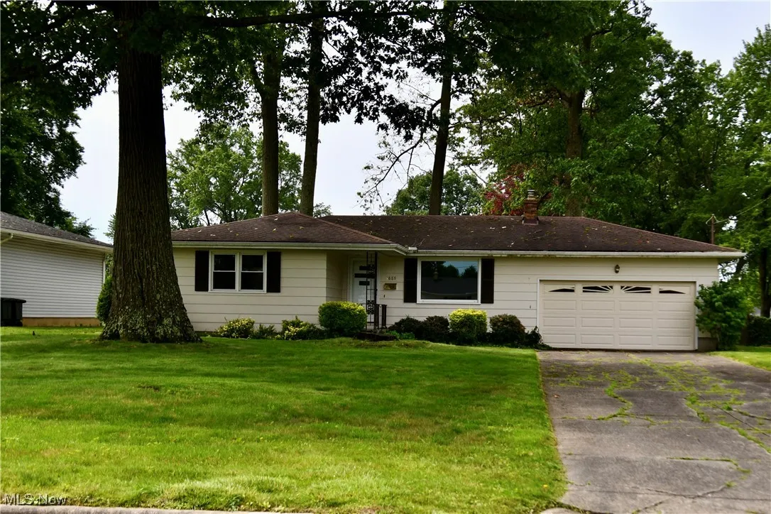 Single story home featuring driveway, a garage, a front lawn, and a chimney