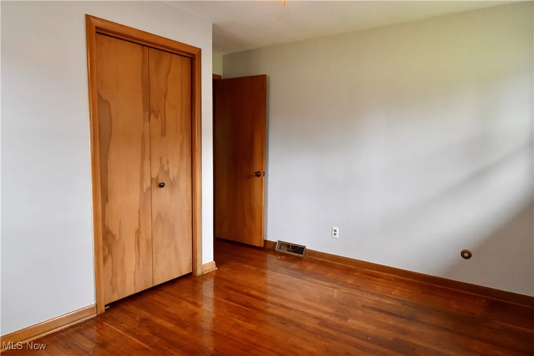 Unfurnished bedroom with wood finished floors and a closet