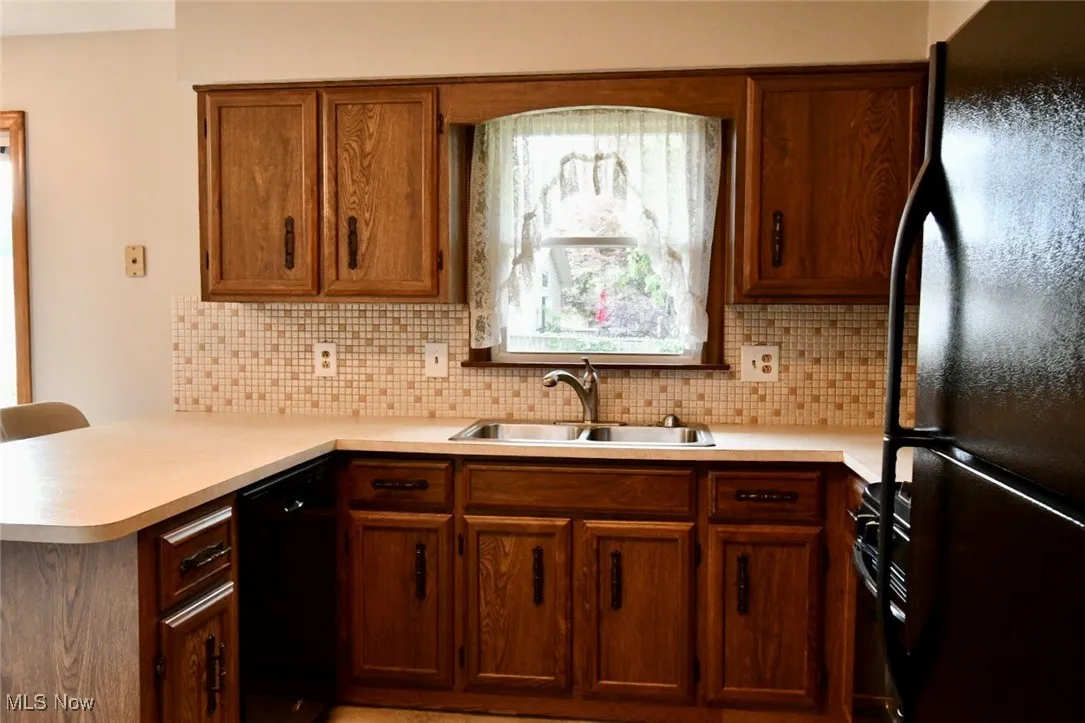 Kitchen with black appliances, light countertops, and decorative backsplash