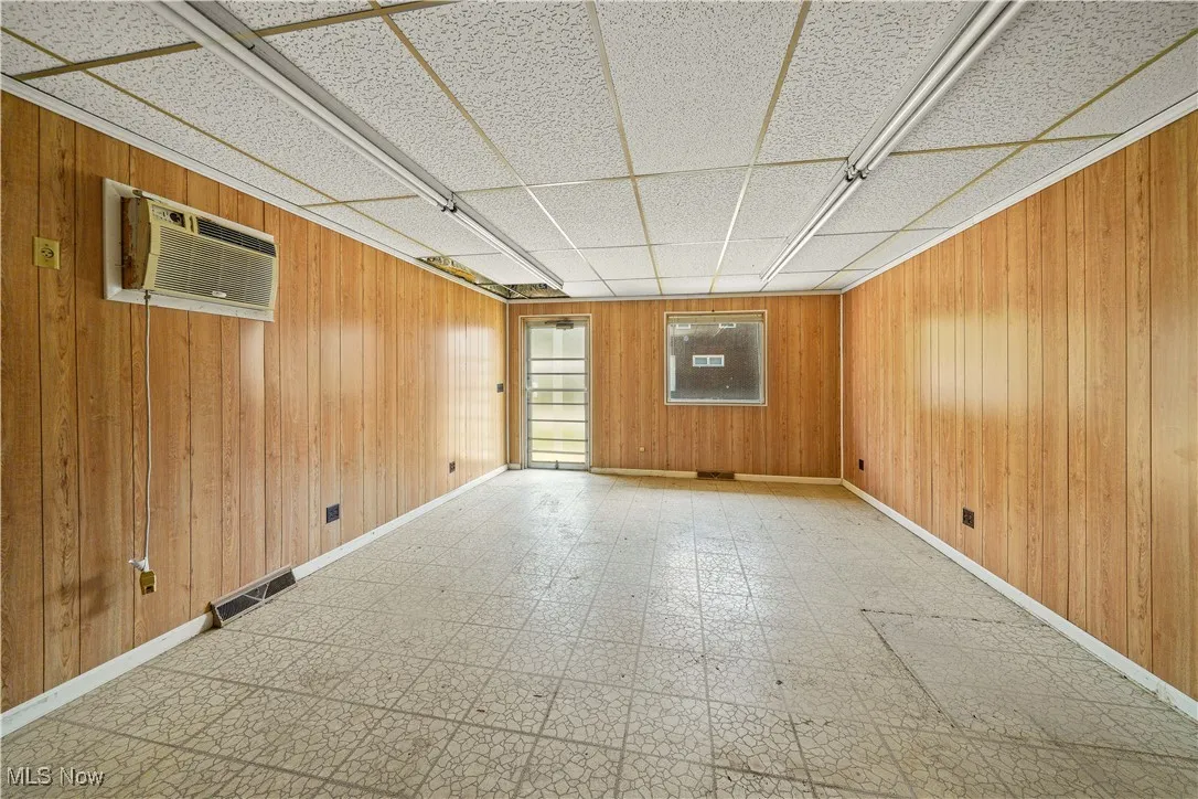 Unfurnished room with tile patterned floors, wooden walls, and a wall mounted AC