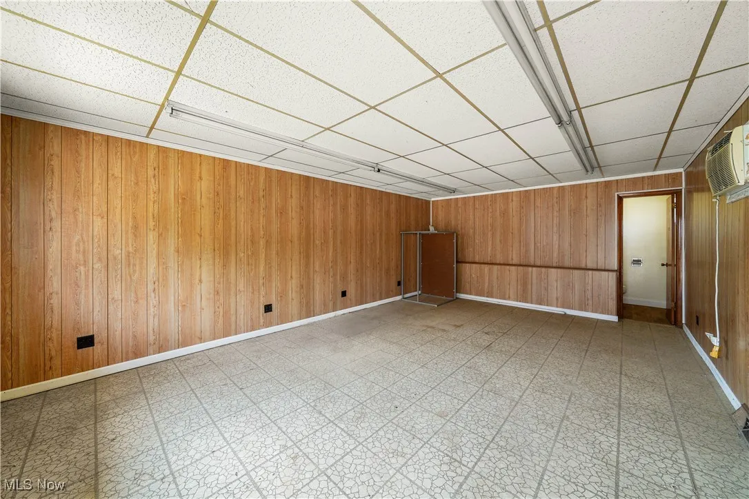 Spare room with tile patterned floors, wood walls, a paneled ceiling, and an AC wall unit