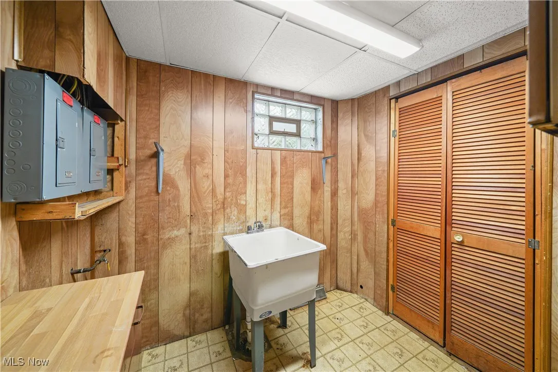 Bathroom with tile patterned floors, wood walls, and electric panel