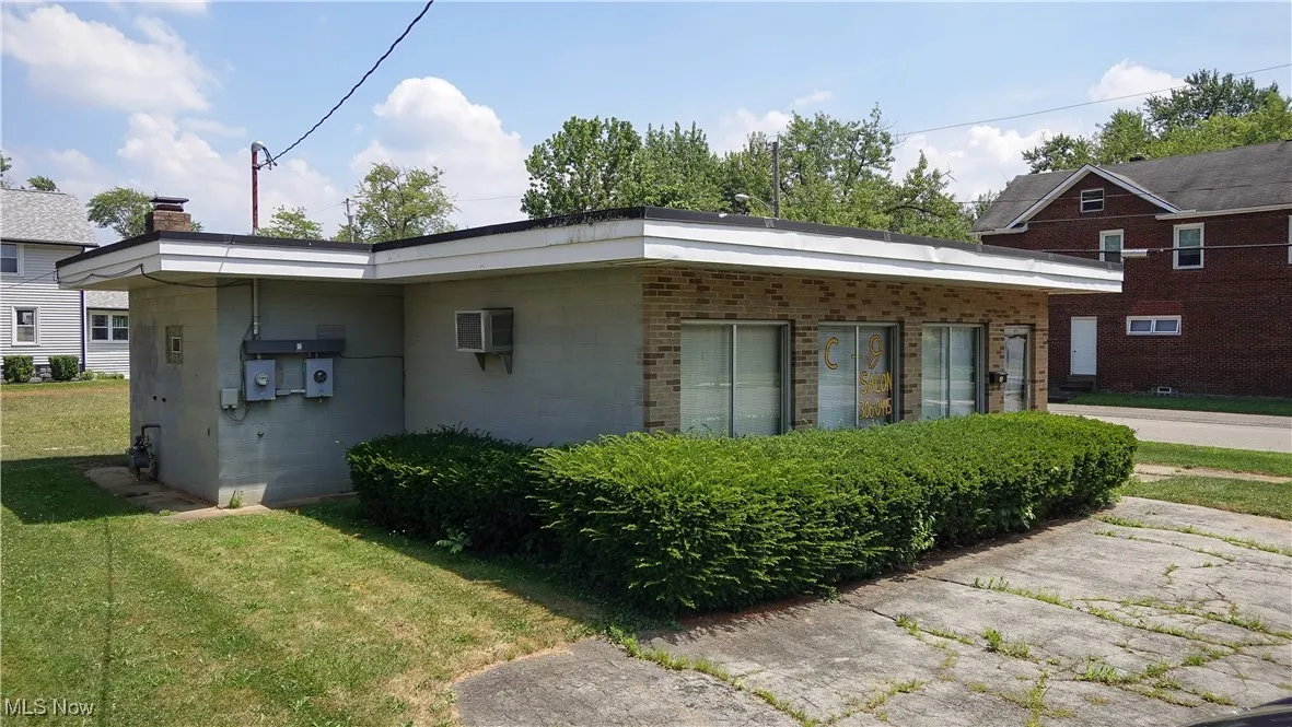 View of side of home featuring concrete block siding and a yard