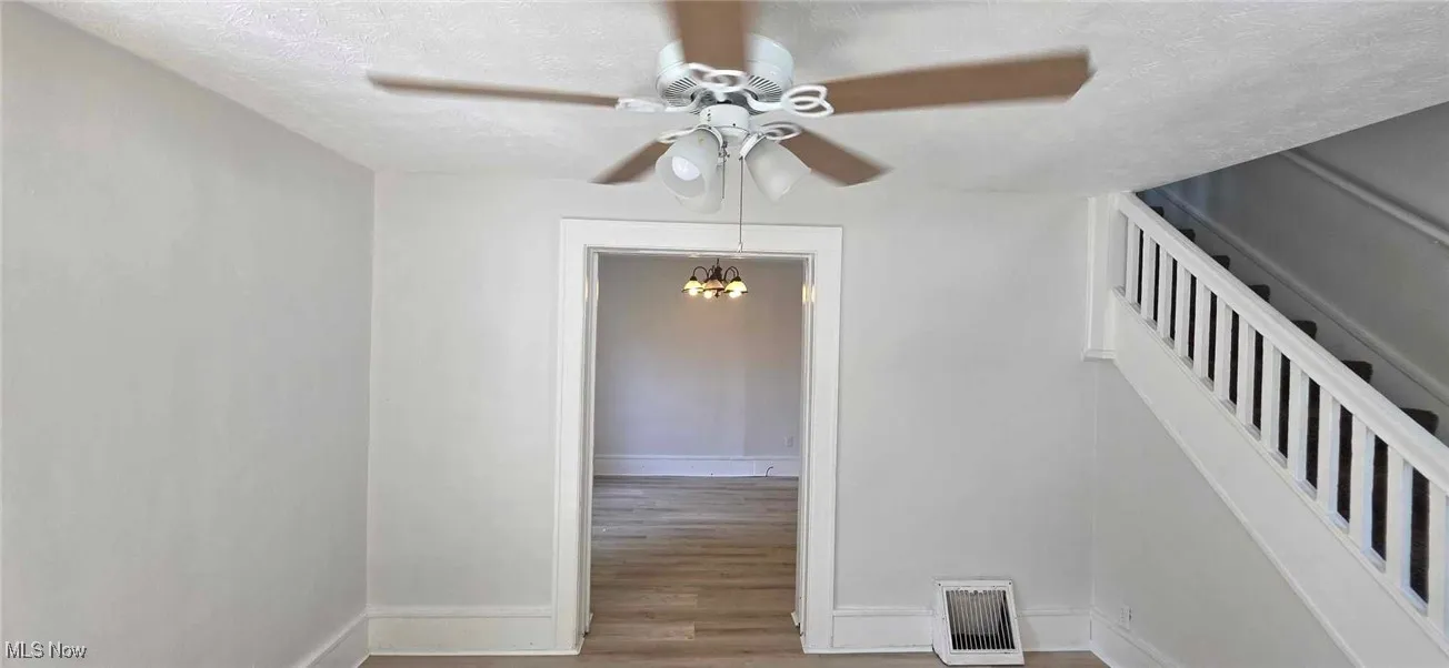 Stairway featuring a textured ceiling, a ceiling fan, lvt floors, and a ceiling fan
