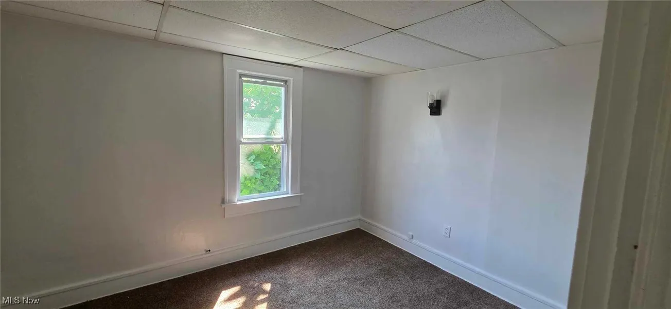 bedroom with a paneled ceiling and dark colored carpet