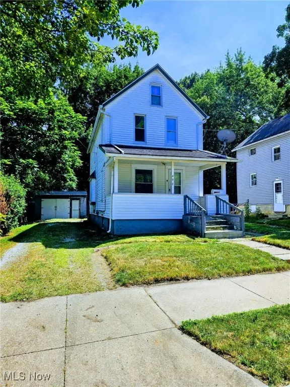 View of front facade featuring covered porch, an outdoor structure, driveway, and a front lawn