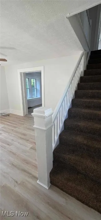 Stairs with carpet and a textured ceiling