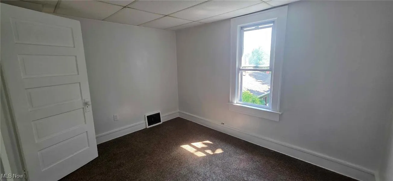 bedroom with dark colored carpet and a paneled ceiling