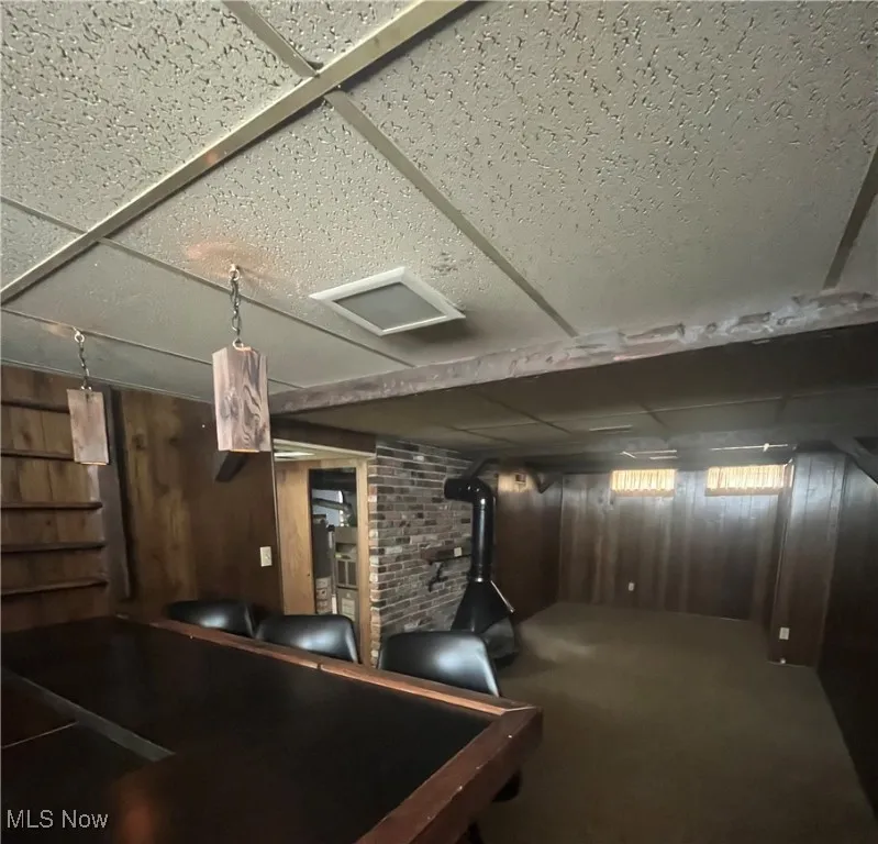 Basement recreation room with paneled walls, beamed ceiling, wet bar and gas fireplace