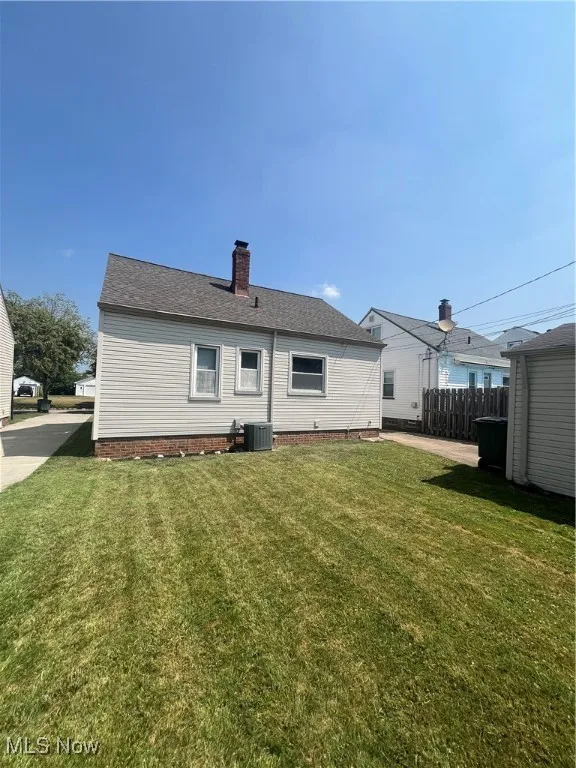 Back of house with a chimney and a shingled roof