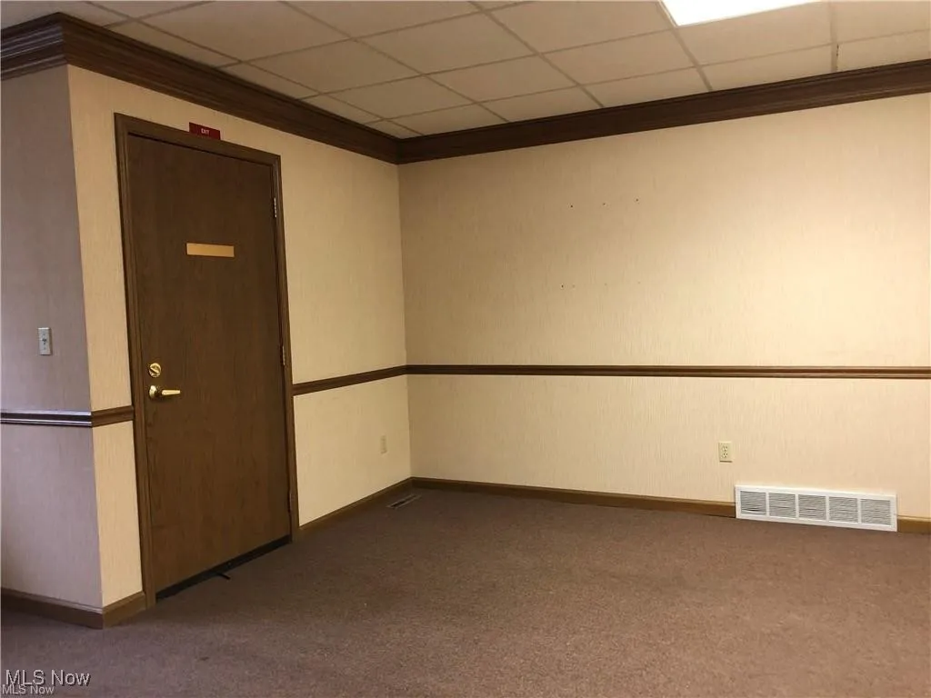 Empty room with ornamental molding, carpet floors, and a paneled ceiling