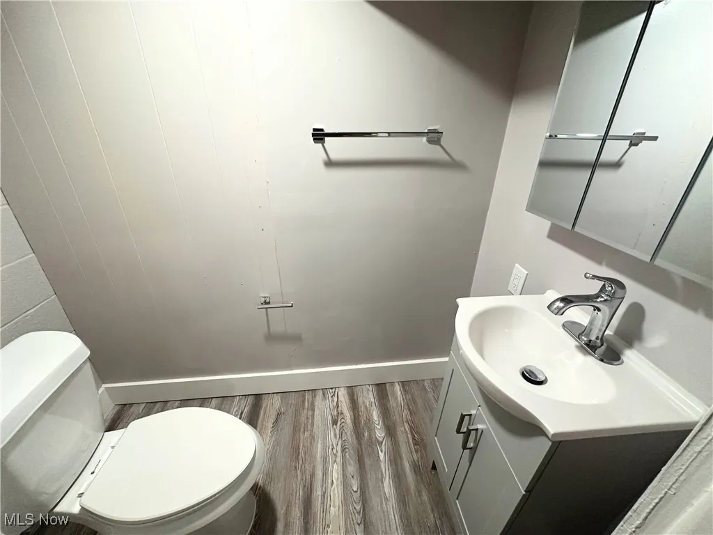 Half bath featuring wood finished floors and vanity