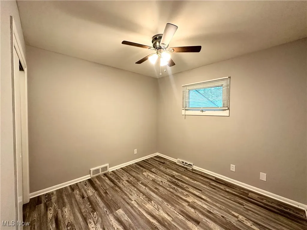 Empty room with dark wood-style floors and ceiling fan