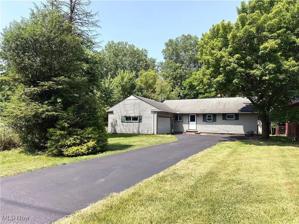 Single story home featuring a garage, a front lawn, and driveway